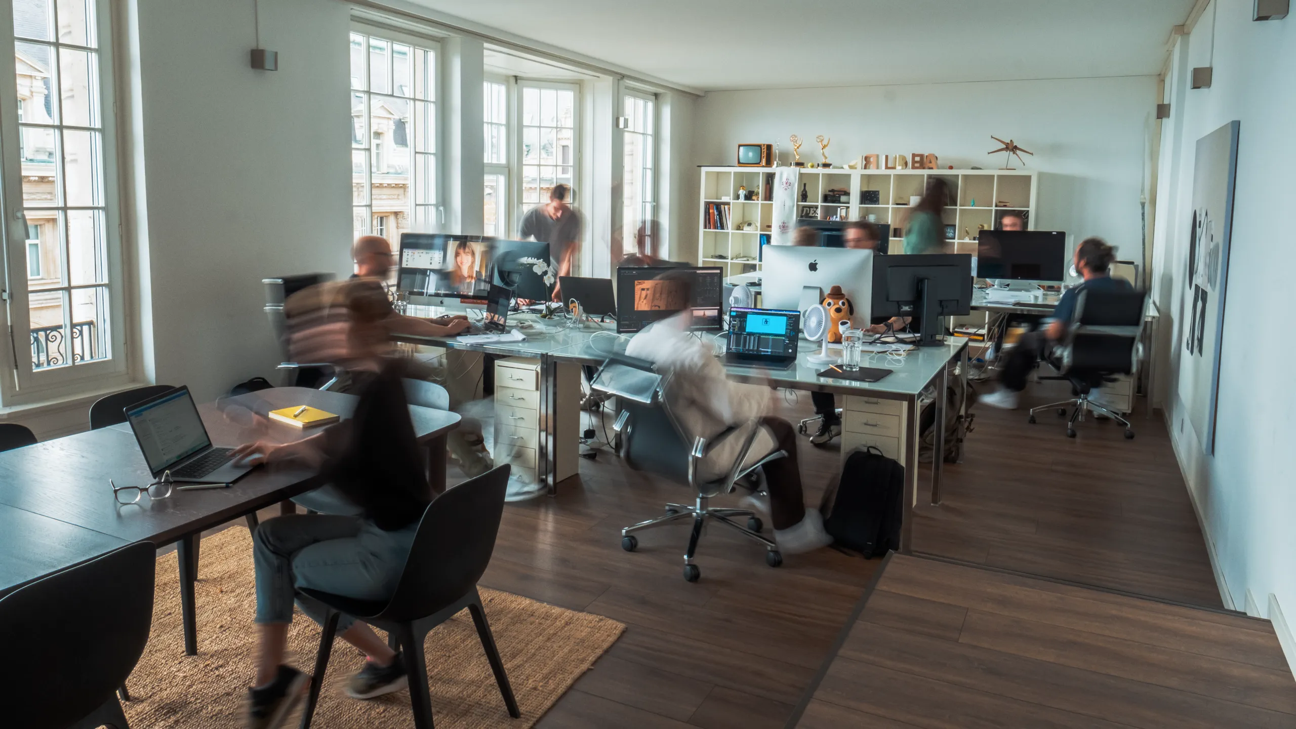 Agency office with graphic designer, producer, motion designer in front of computer.